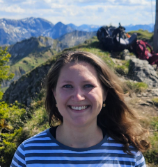 Femme souriante en marinière, sur fond de montagnes et de randonneurs assis sur un rocher